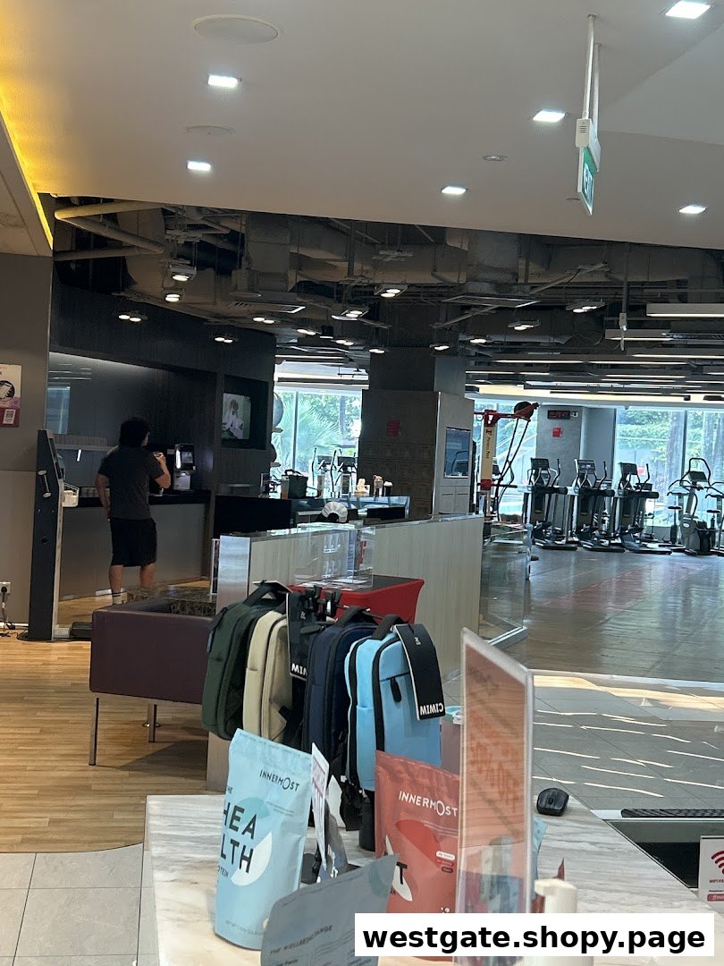 Interior view of Fitness First gym, showing exercise equipment, a reception area, and a person at the counter.