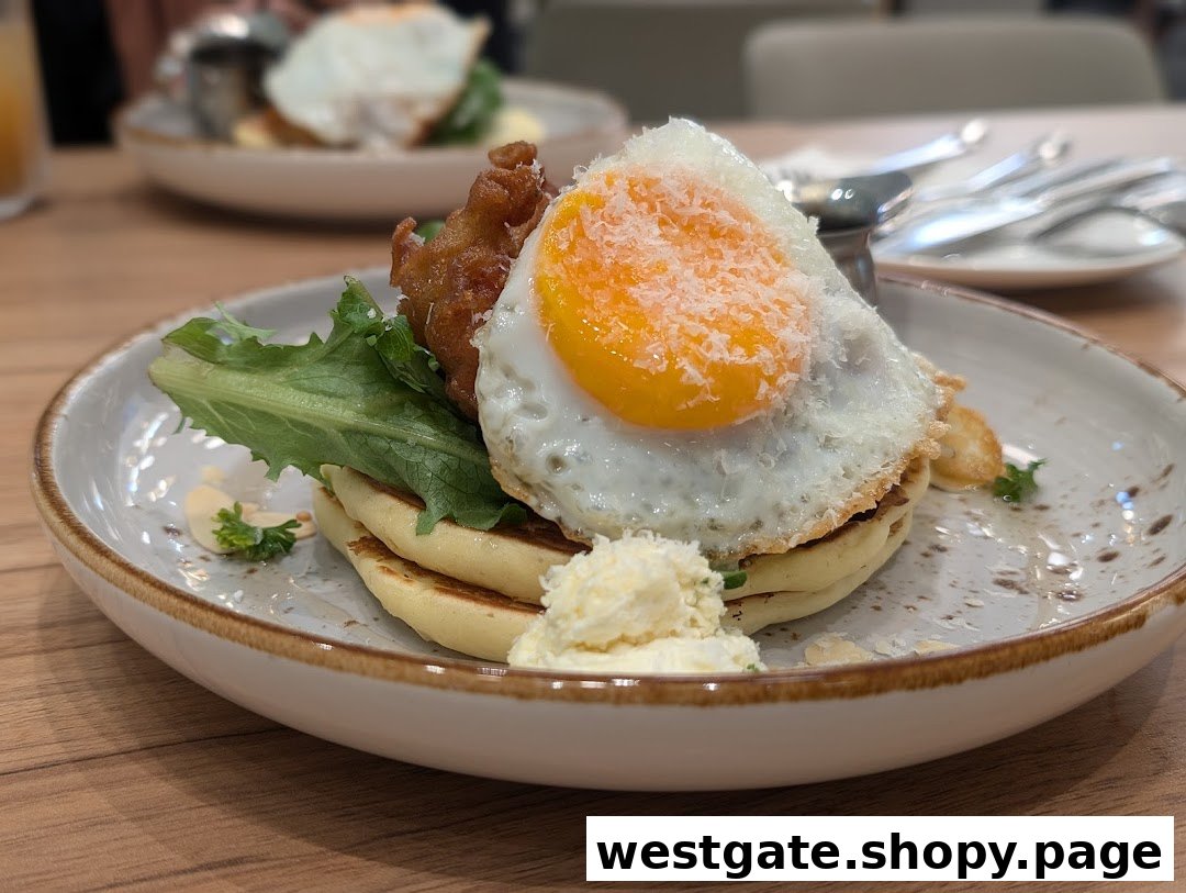 A close-up of a delicious dish featuring pancakes, a fried egg, fried chicken, and greens.