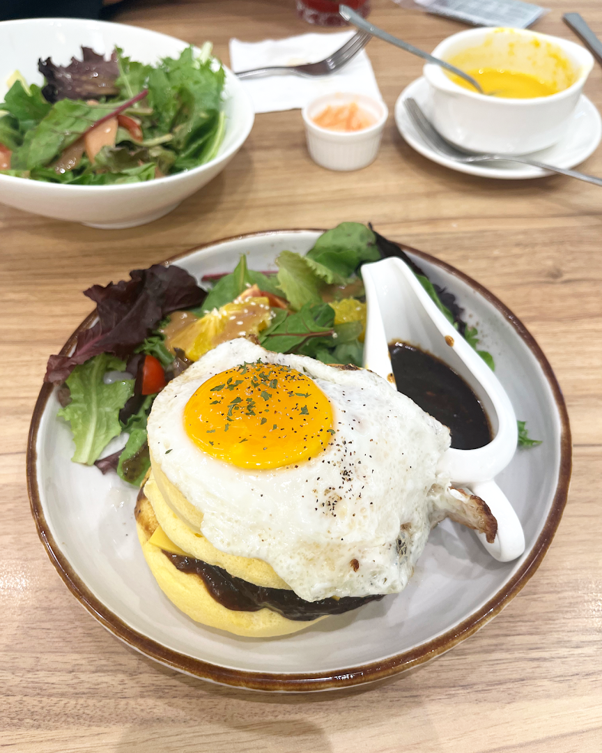 A delicious dish featuring a fried egg, pancakes, and a fresh side salad with gravy at Flippers Westgate.