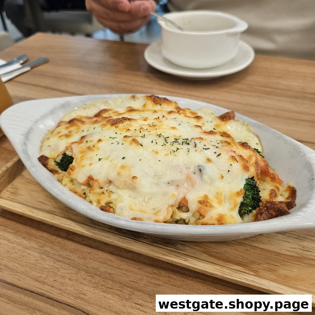 A close-up of a delicious baked dish with melted cheese, salmon, and broccoli served on a wooden tray.