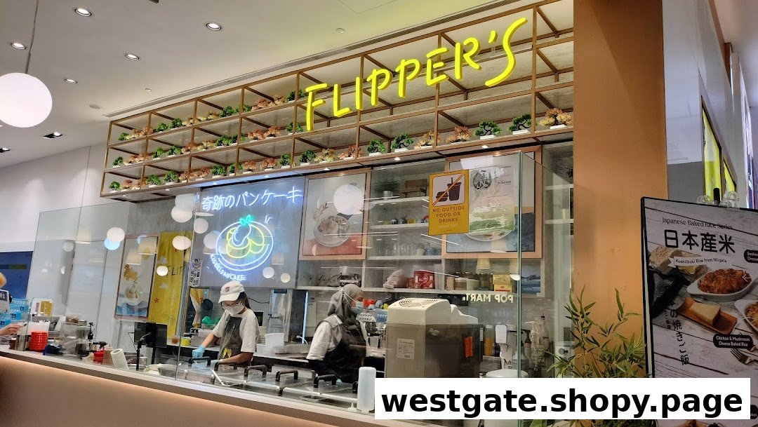 An interior view of Flippers Westgate, showcasing the counter, staff, and vibrant neon signage for their famous pancakes.