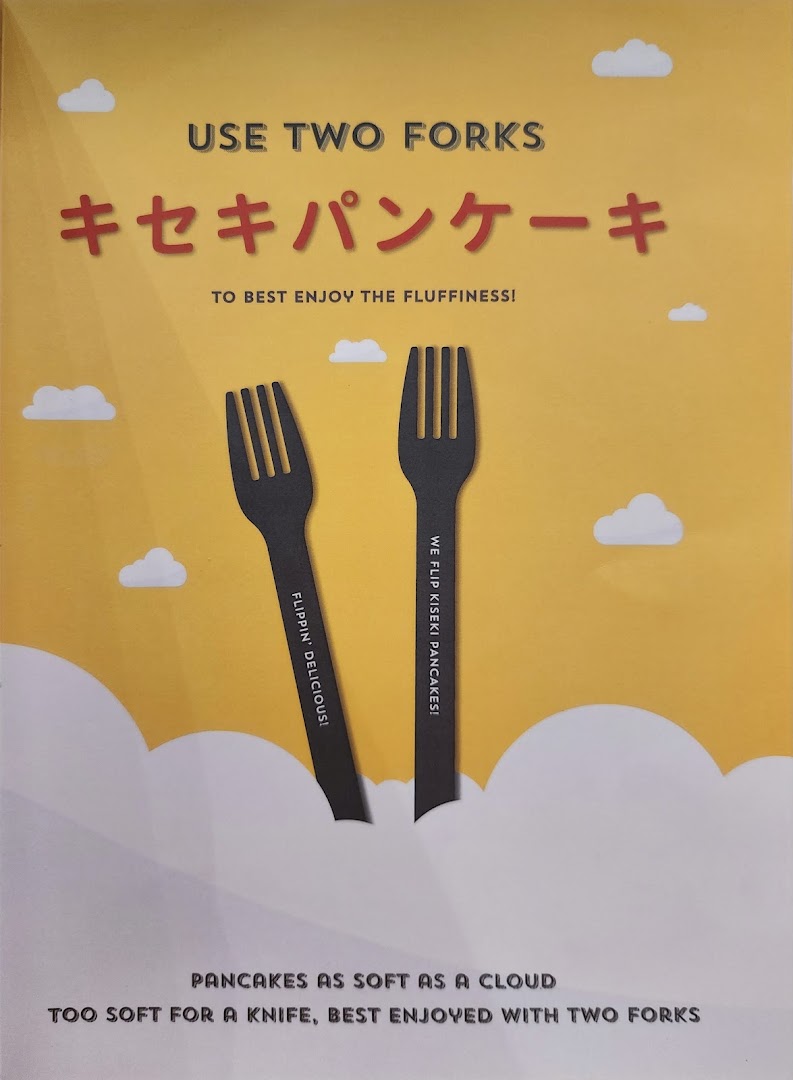 A vibrant yellow sign promoting Flippers' incredibly soft Kiseki pancakes, emphasizing their unique two-fork eating experience.