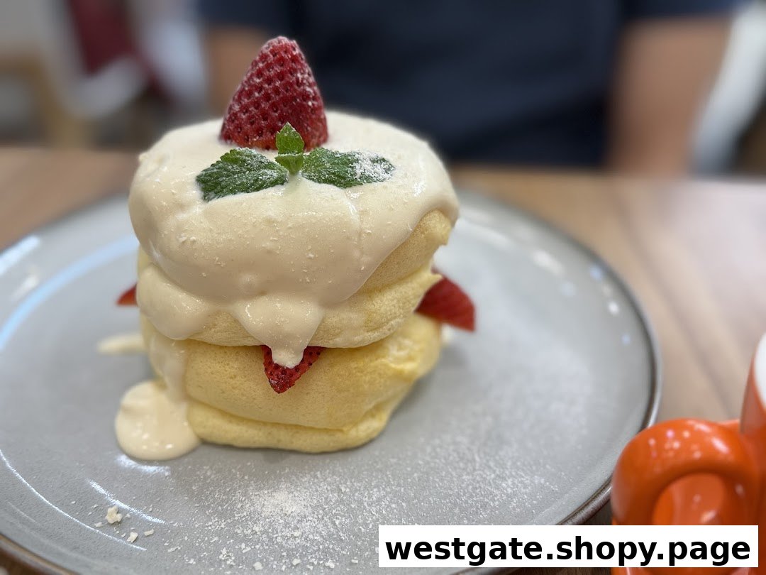 A stack of fluffy soufflé pancakes topped with cream, strawberries, and mint on a grey plate.