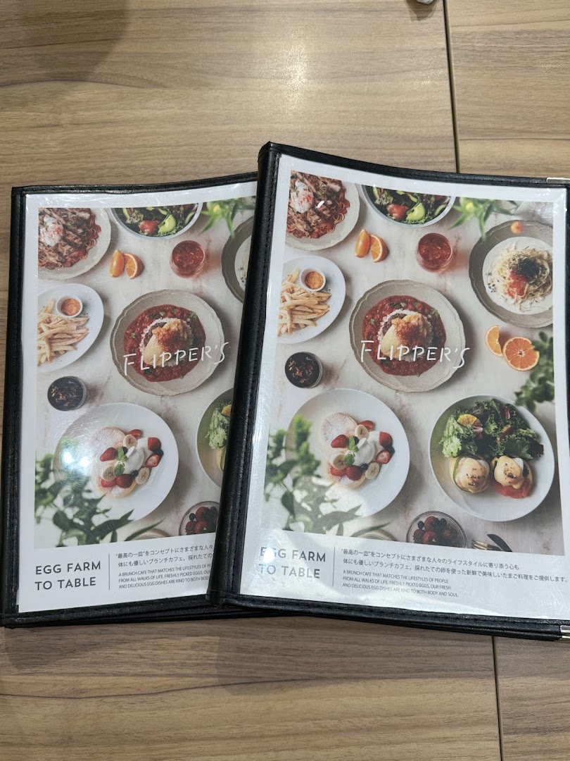 Two open menus from FLIPPER'S showcasing various egg-based dishes, pancakes, and their 'Egg Farm to Table' concept.