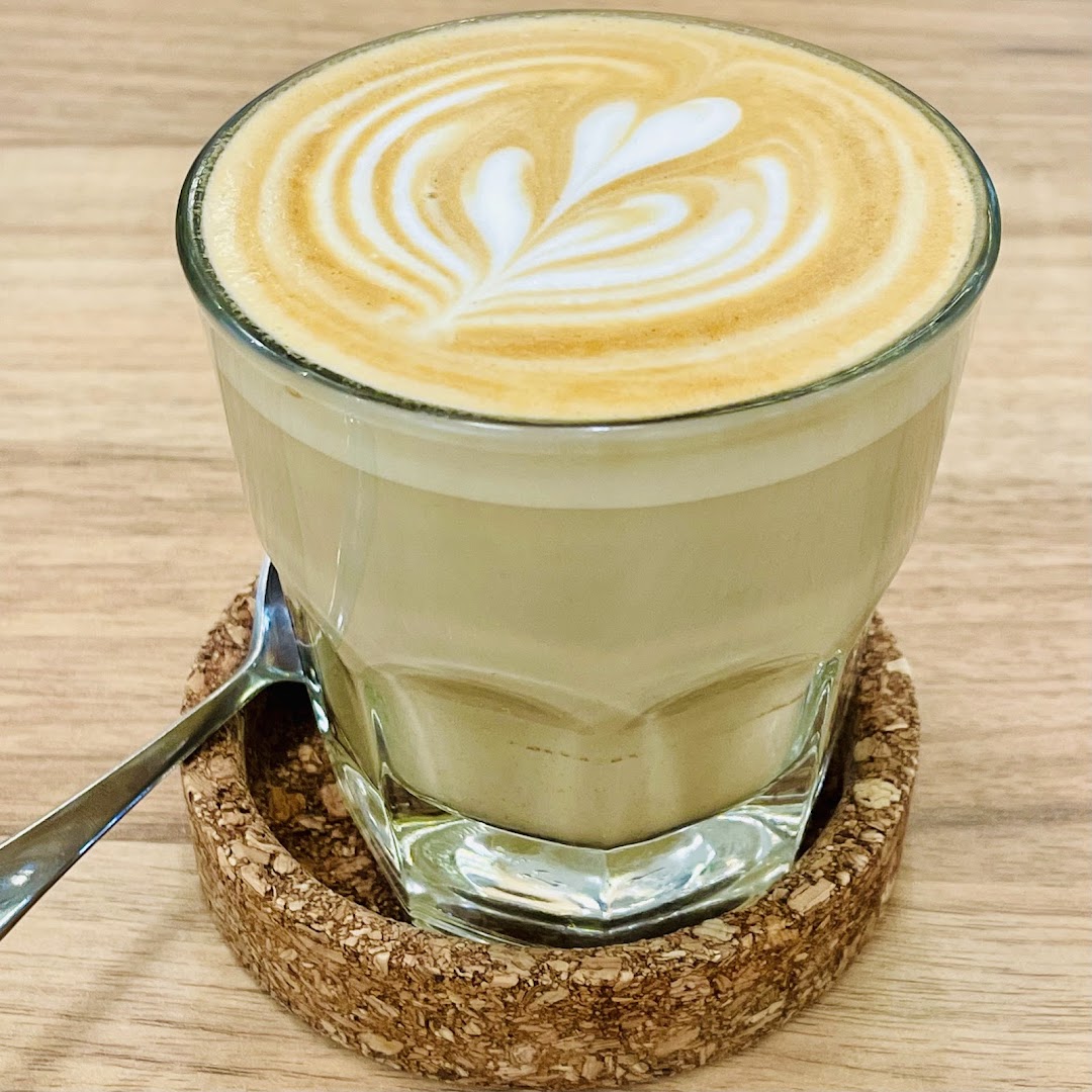 A close-up of a beautifully crafted latte with heart-shaped latte art on a cork coaster.