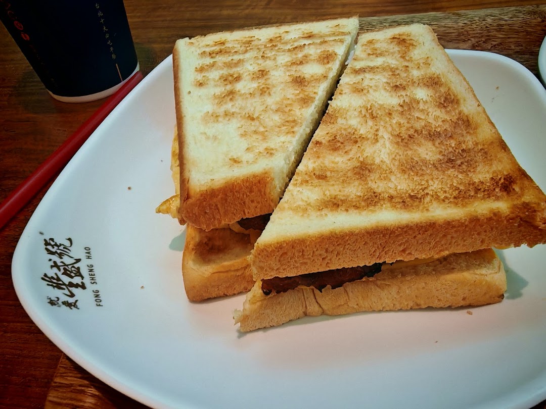 A perfectly toasted sandwich, cut in half, served on a white plate with a drink.