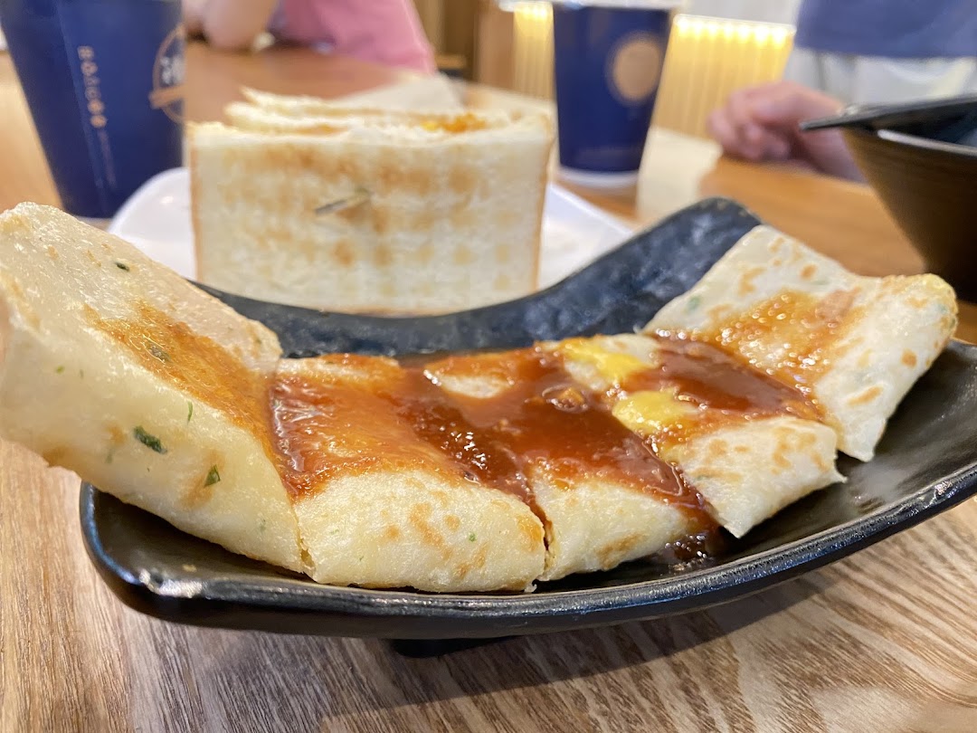 Close-up of a savory pancake dish with sauce, served on a black plate at Fong Sheng Hao.