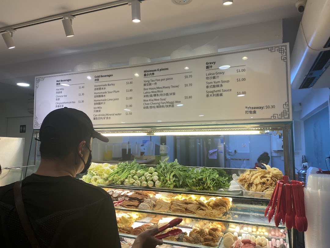 A customer views a menu board displaying beverages, Yong Tau Foo, and gravy options.