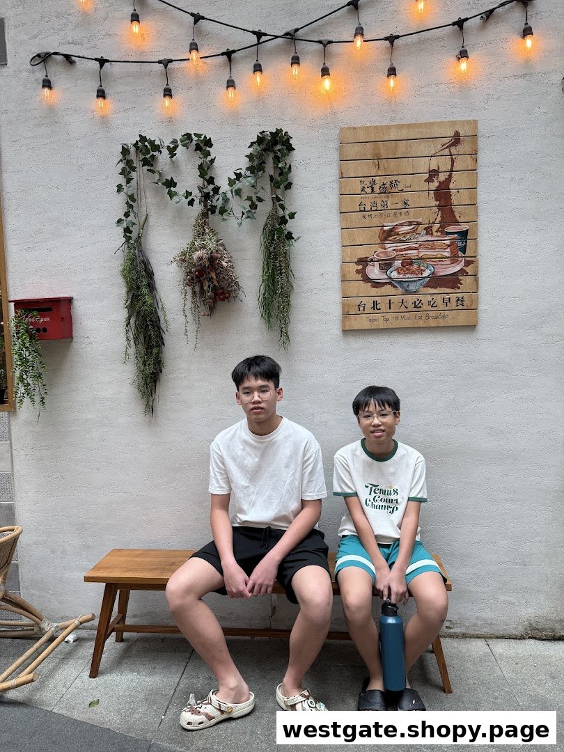 Two individuals relaxing on a wooden bench outside Fong Sheng Hao, featuring decorative lighting and a breakfast sign.
