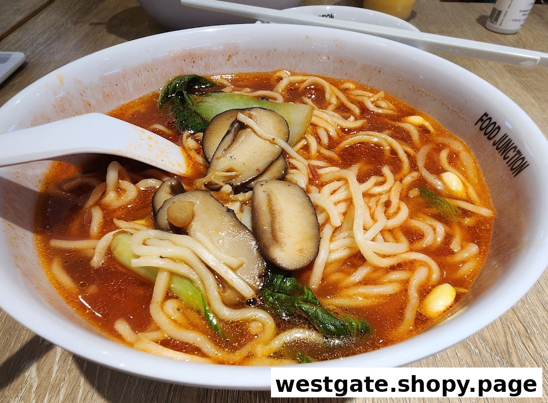 A close-up of a delicious bowl of spicy noodles with mushrooms and greens from Food Junction.