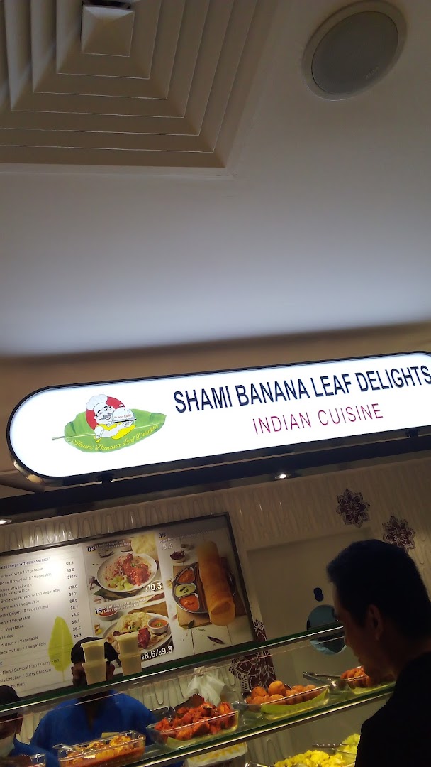 An Indian cuisine food stall, Shami Banana Leaf Delights, with a menu board and food displays.