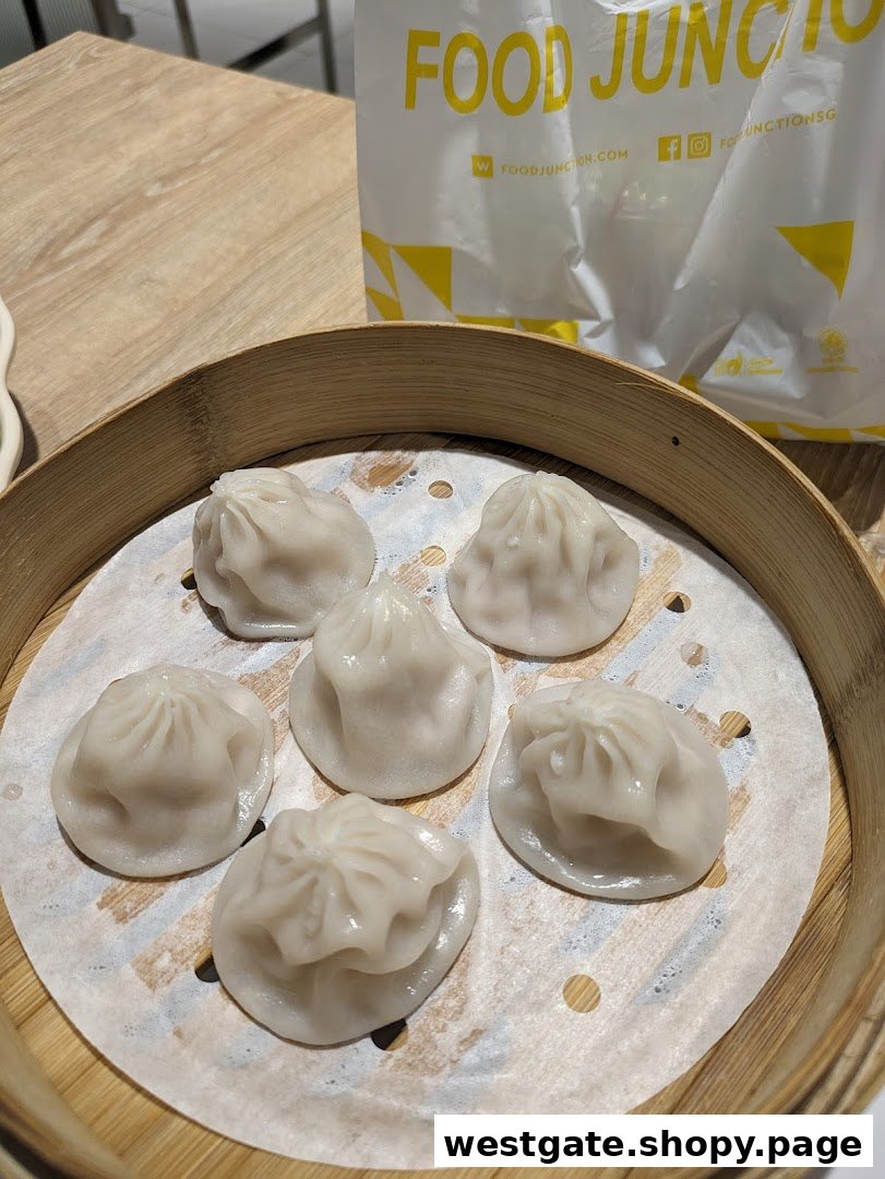 A bamboo steamer basket filled with freshly steamed dumplings, with a Food Junction bag in the background.