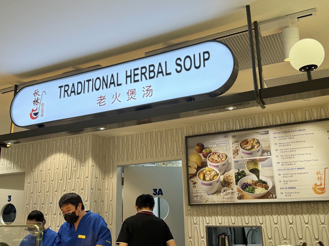 A stall named Traditional Herbal Soup with staff and a menu board displaying various healthy soups and dishes.