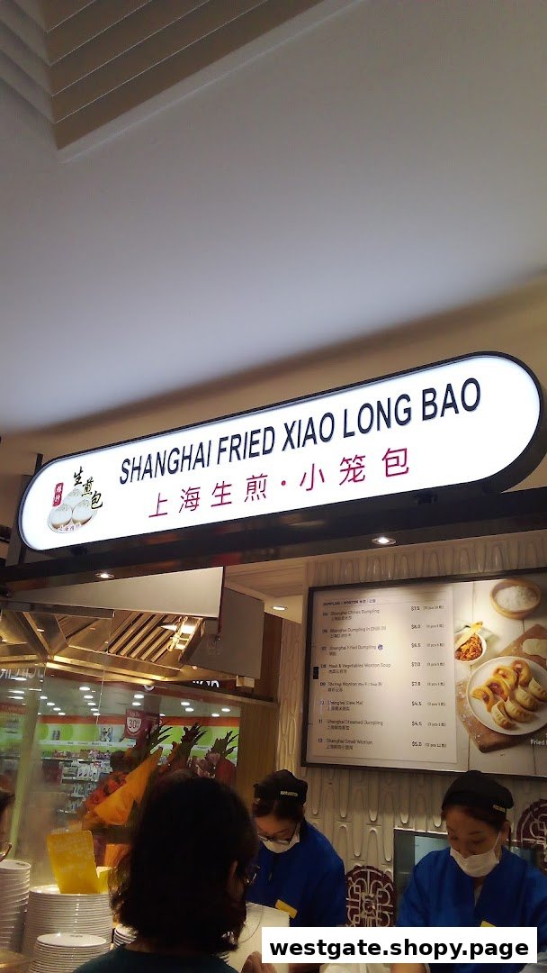 A food stall named 'Shanghai Fried Xiao Long Bao' with staff and a visible menu board.
