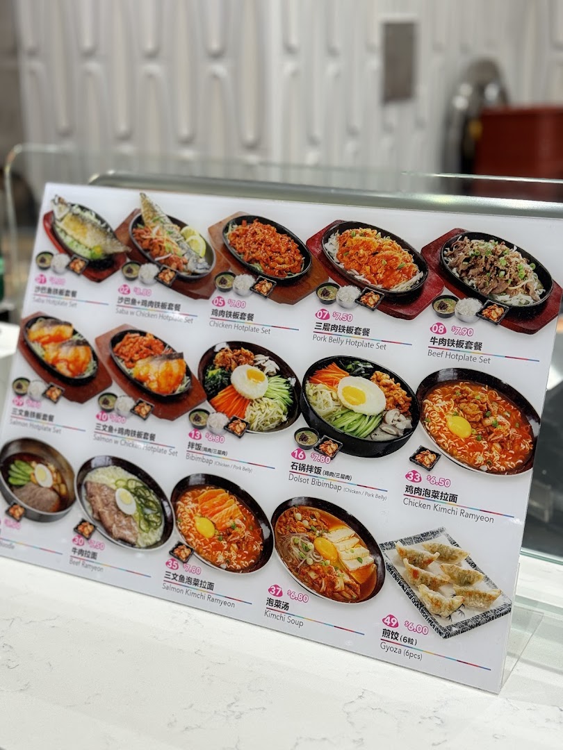 A vibrant menu display showcasing various hotplate sets, bibimbap, ramyeon, and gyoza.
