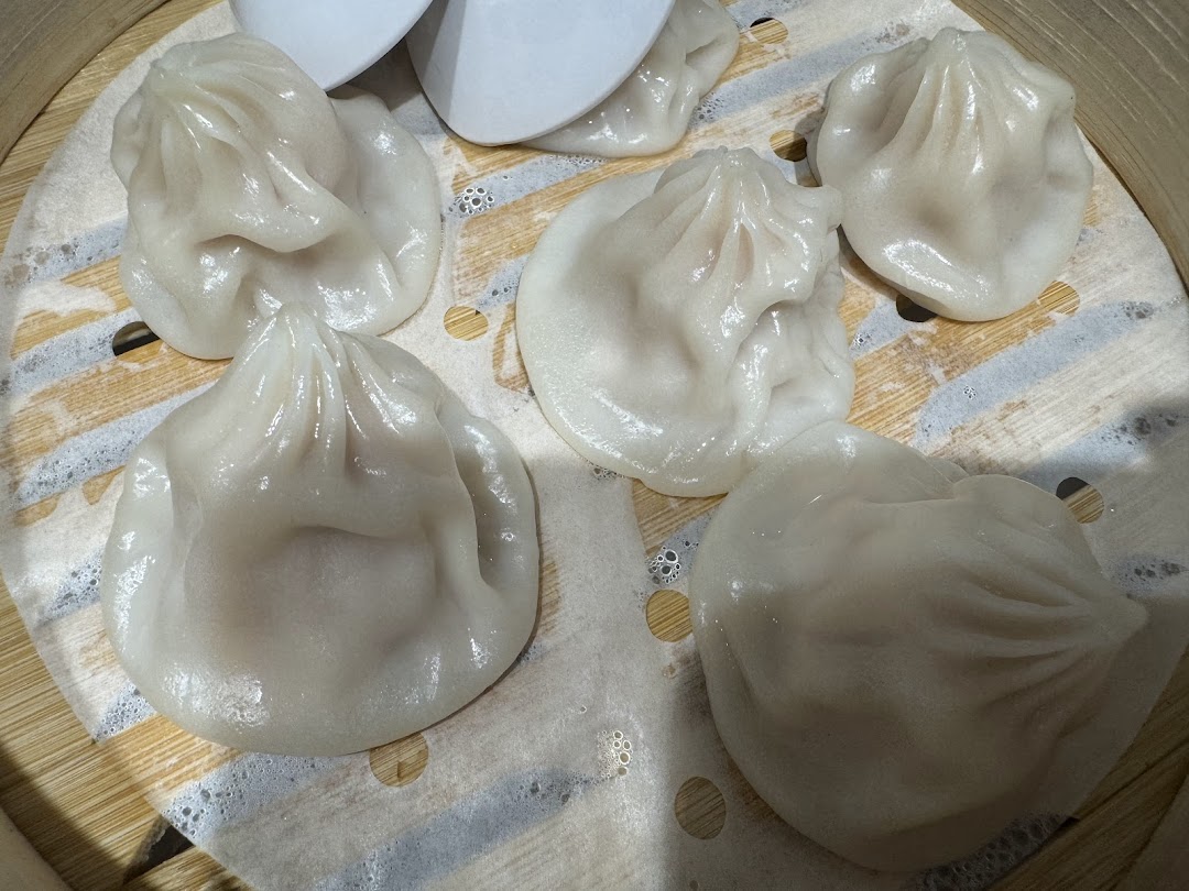 Freshly steamed soup dumplings (xiao long bao) in a bamboo steamer.