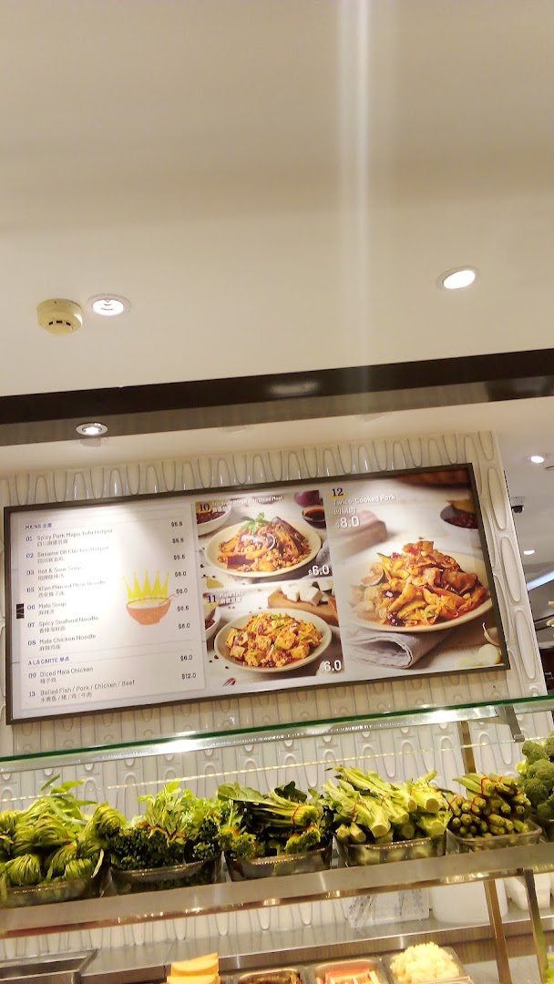A digital menu board displaying various Chinese dishes and prices, with fresh vegetables on display below.