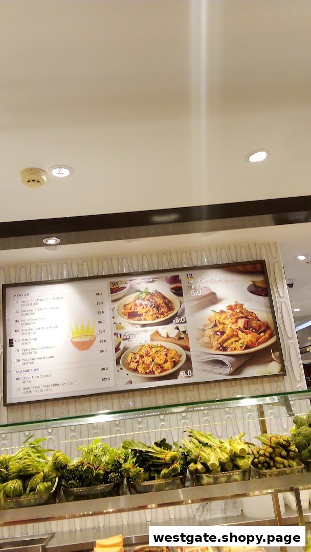 A digital menu board displaying various Chinese dishes and prices, with fresh vegetables on display below.