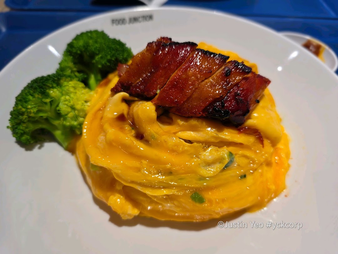 A plate of creamy scrambled eggs with roasted pork belly and fresh broccoli.