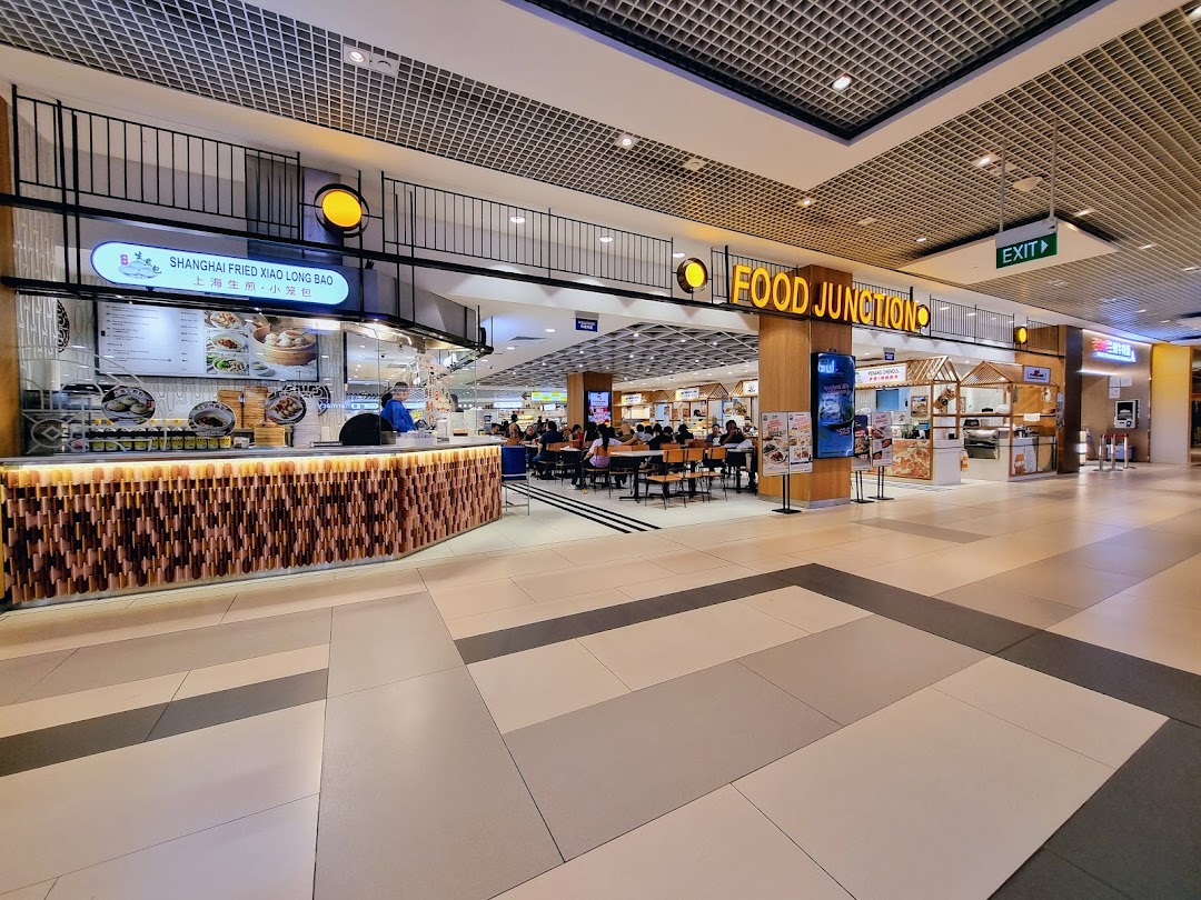 A bustling food court entrance with various stalls and dining areas, featuring the 'Food Junction' sign.