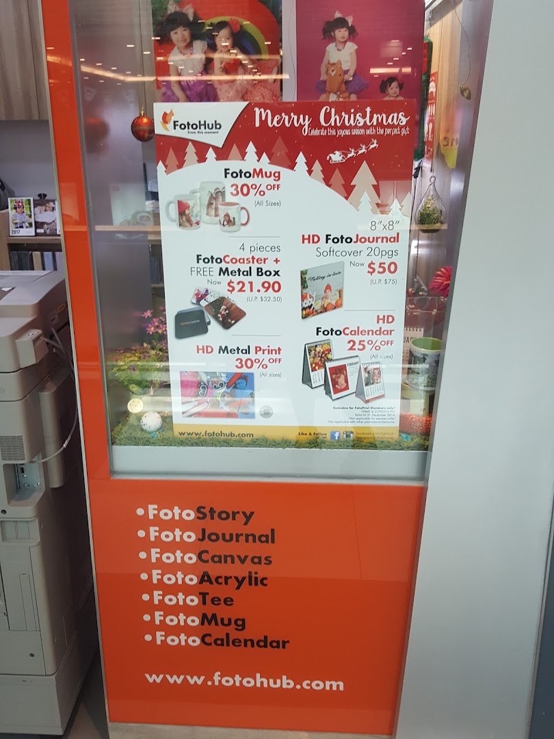 A FotoHub display showcasing personalized photo products and Christmas promotions like FotoMugs, FotoCoasters, and FotoJournals.