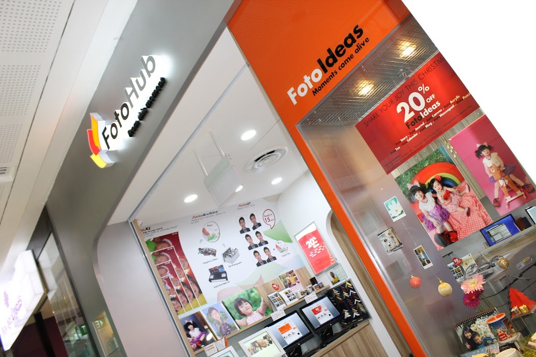 The image shows the vibrant orange and white storefront of FotoHub, a photo printing and personalized gift shop.
