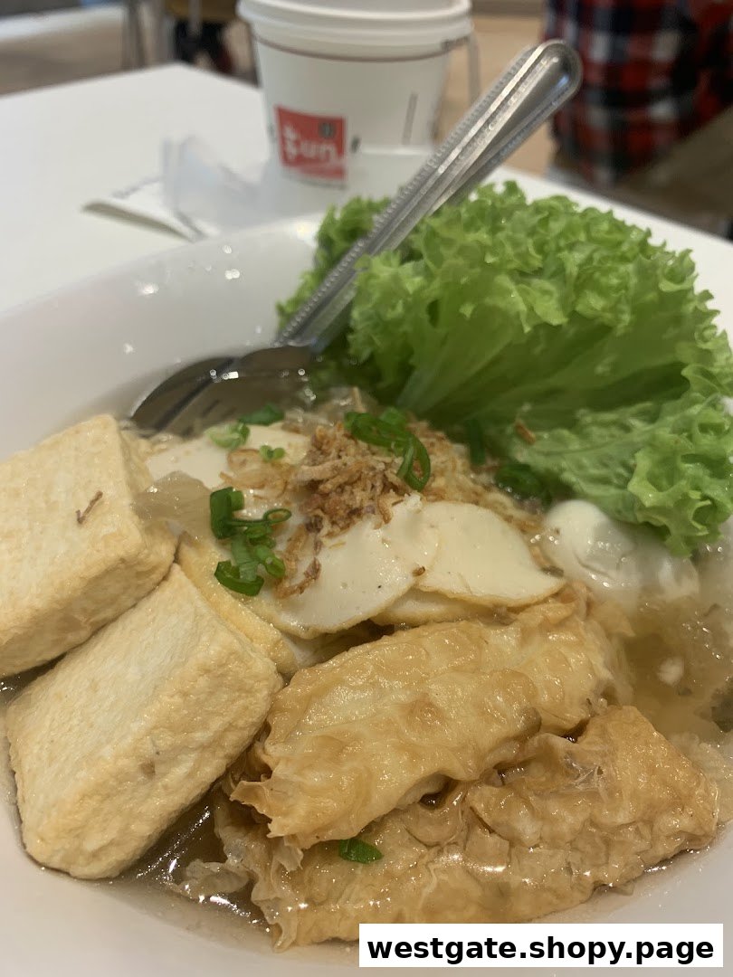 A close-up of a savory noodle dish with tofu, fish cakes, and fresh lettuce.