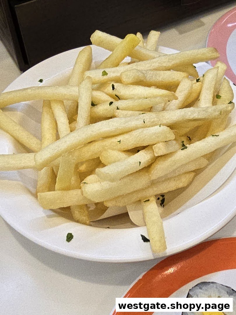 A close-up of golden french fries sprinkled with herbs, served on a white plate.