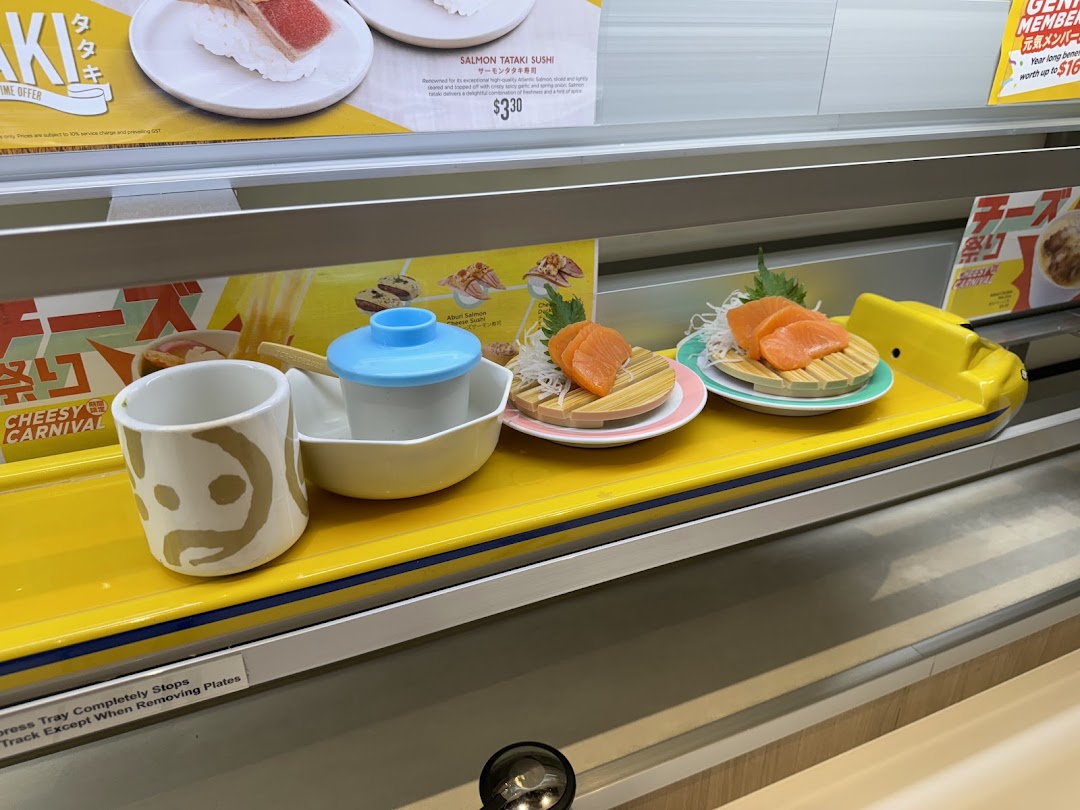 A vibrant view of Genki Sushi's conveyor belt, featuring fresh salmon sashimi and unique dining ware.