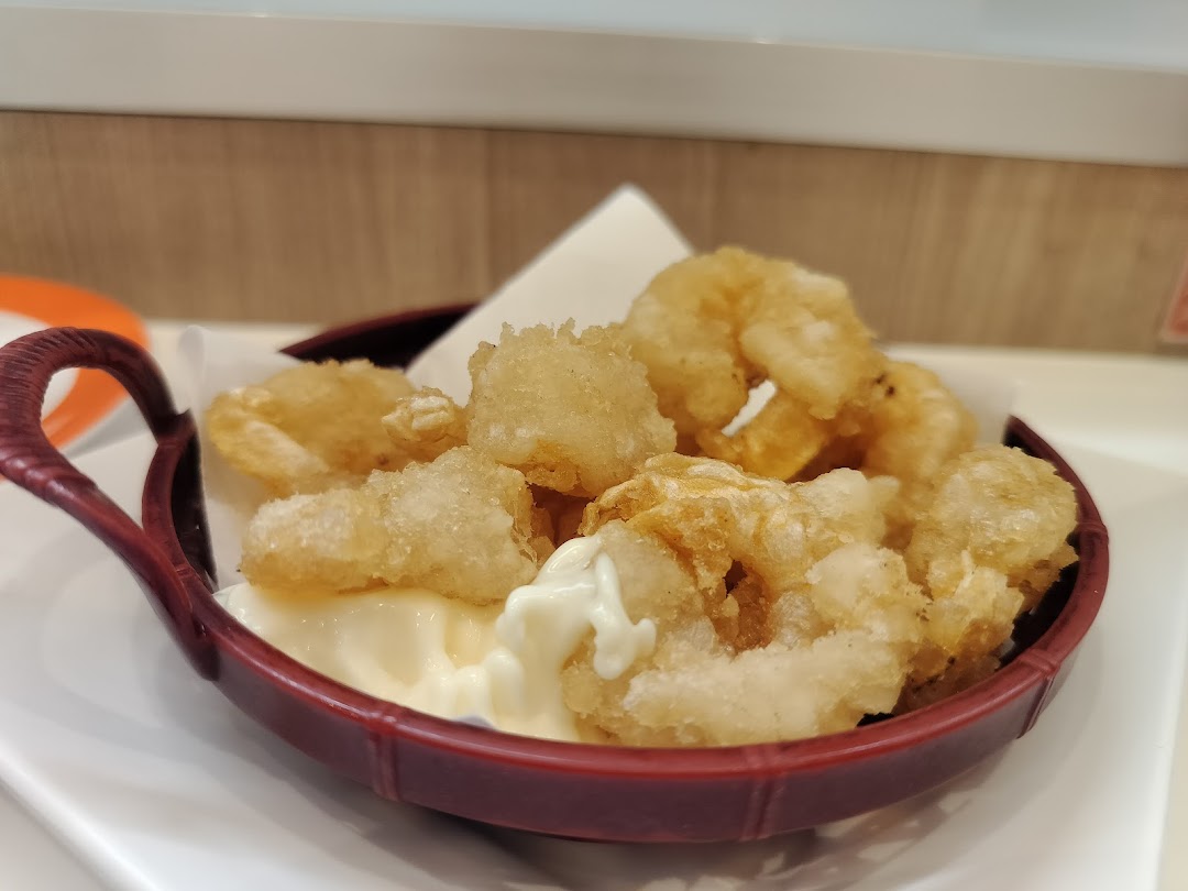 A close-up of crispy fried tempura or calamari with mayonnaise in a red serving bowl.