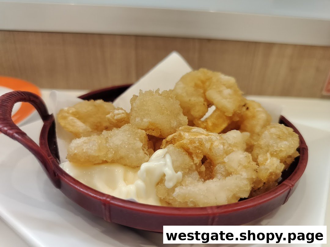 A close-up of crispy fried tempura or calamari with mayonnaise in a red serving bowl.