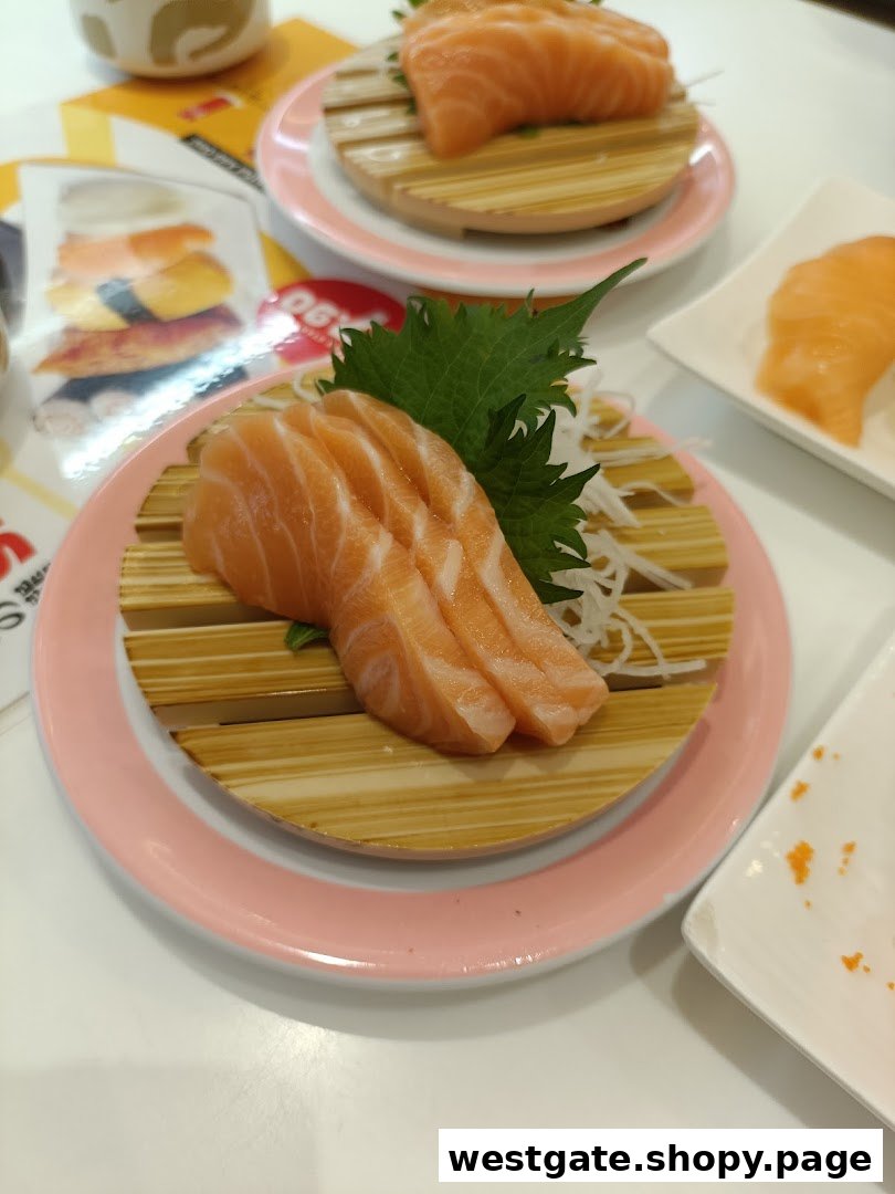 Fresh salmon sashimi and sushi served on pink plates at Genki Sushi.