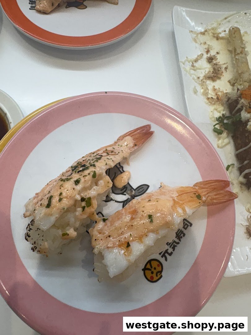 Two pieces of delicious shrimp sushi with sauce on a branded pink plate at Genki Sushi.