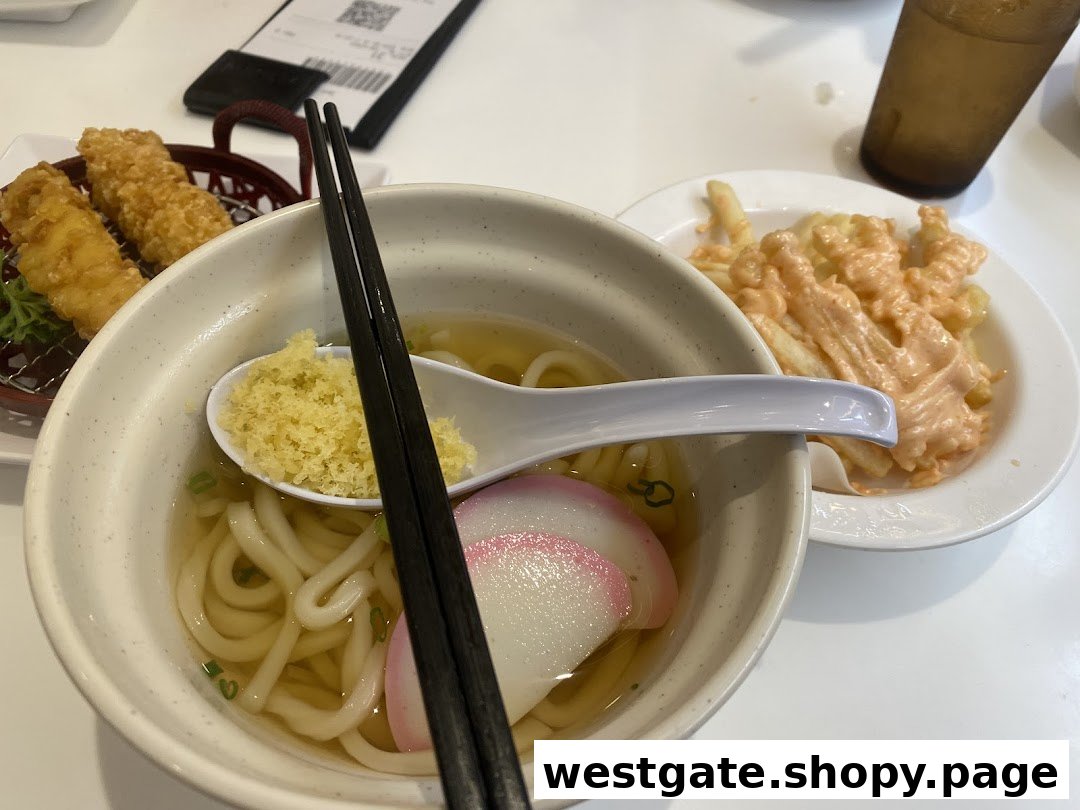 A table spread featuring a bowl of udon, crispy tempura, and fries with a creamy sauce.