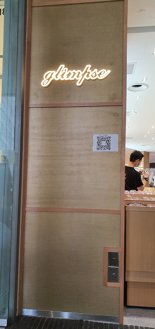 The entrance of Glimpse shop featuring its neon sign and a QR code on a textured wall.