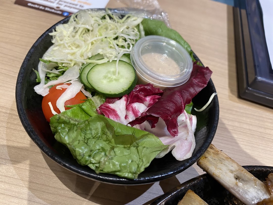 A vibrant garden salad featuring fresh greens, sliced cucumber, cherry tomato, and dressing in a black bowl.