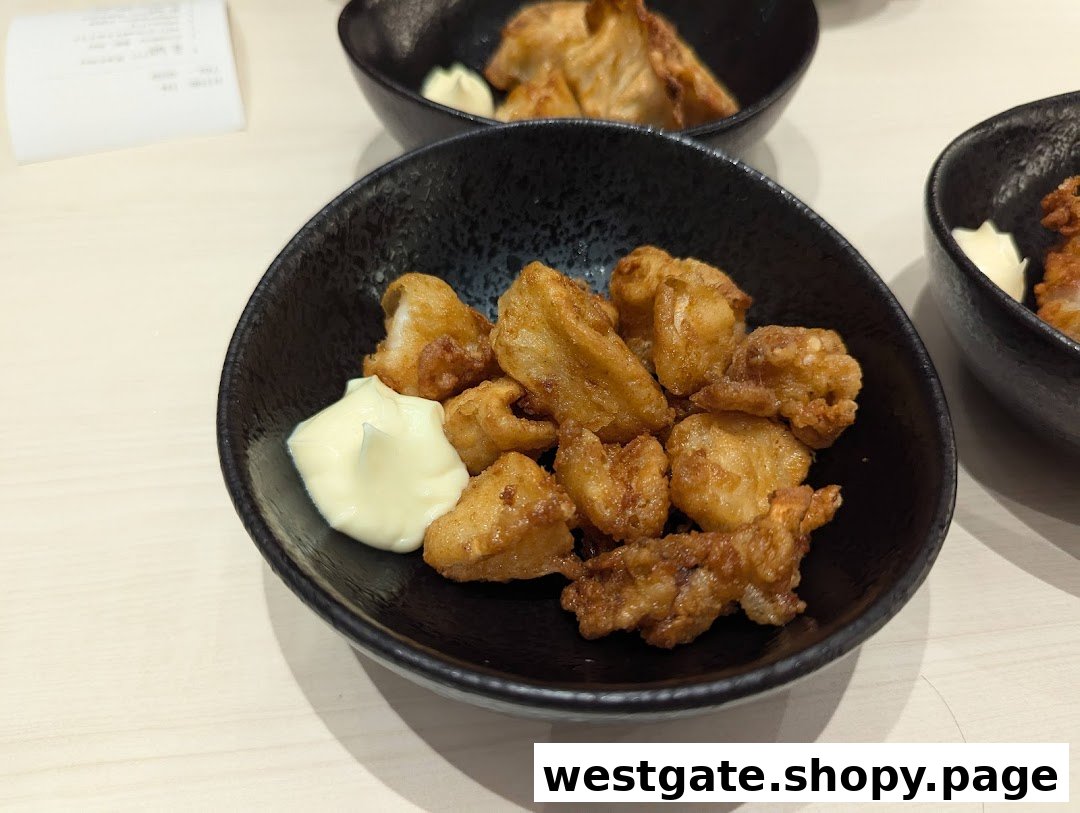 A black bowl filled with golden-brown fried chicken pieces and a dollop of mayonnaise.
