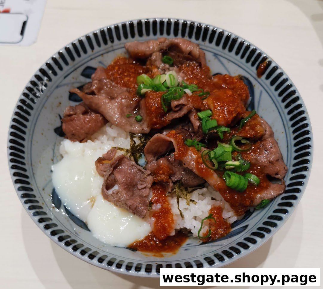 A close-up of a delicious Japanese beef bowl with rice, tender beef slices, spicy sauce, and a poached egg.