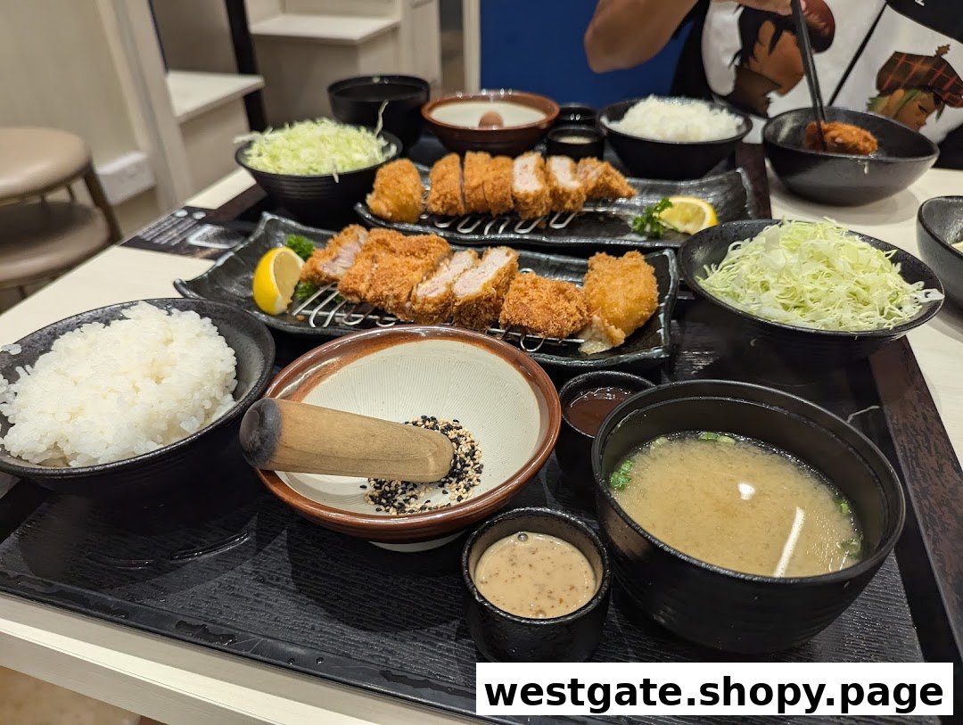 Multiple Japanese tonkatsu sets with rice, shredded cabbage, miso soup, and sesame grinding bowls.