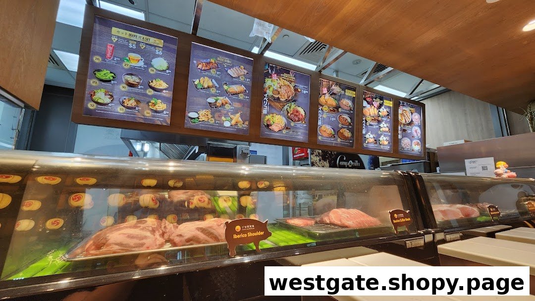 Digital menu boards displaying various Japanese dishes and prices, with a fresh meat display case below.