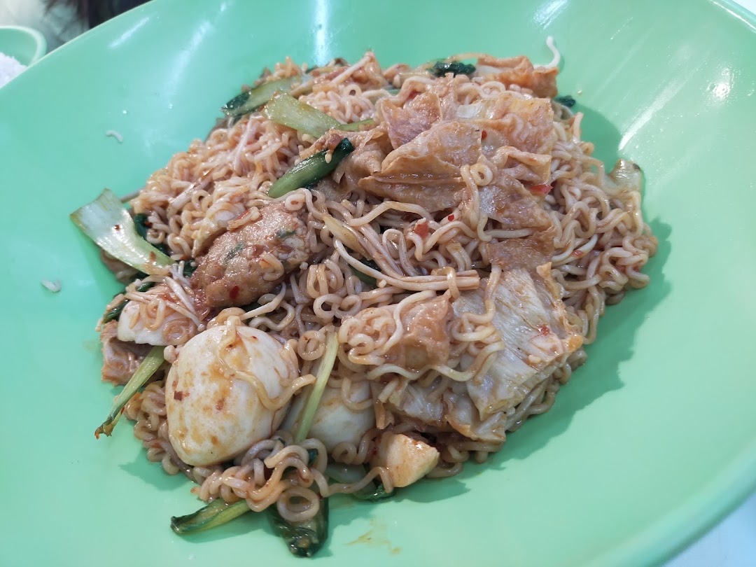 A close-up of a delicious noodle dish with various ingredients served in a vibrant green bowl.