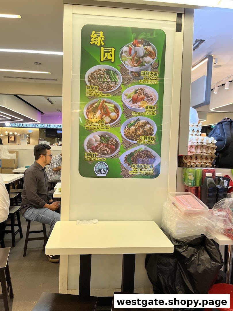A large menu board at Green Delights showcasing various noodle dishes and a steamboat, with customers seated nearby.