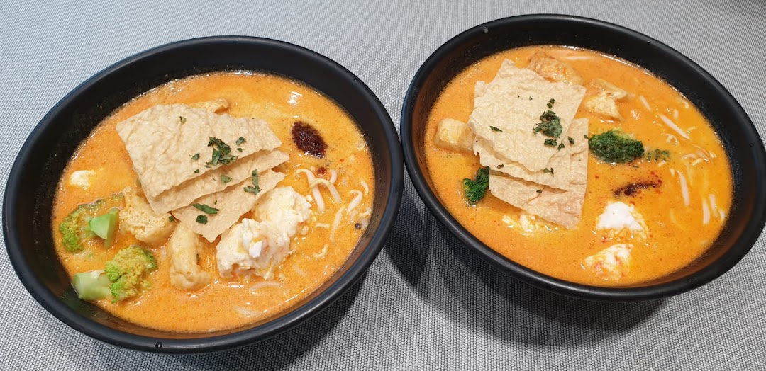 Two vibrant bowls of plant-based curry noodles with tofu, broccoli, and bean curd skin.