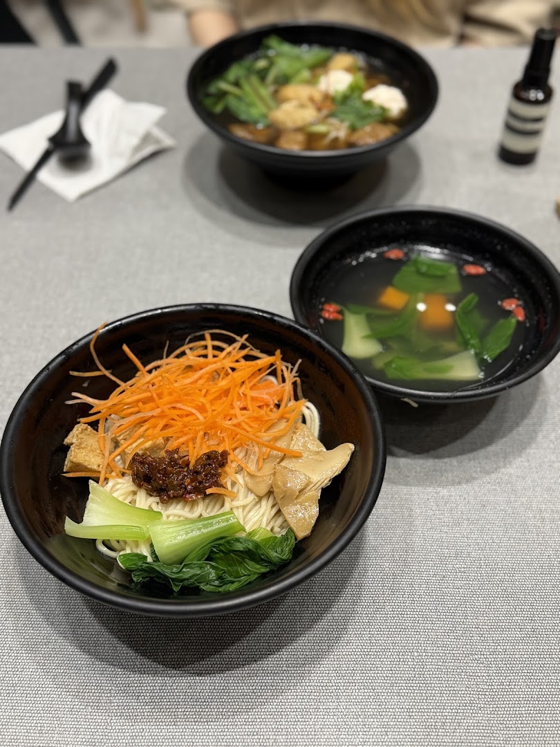Three bowls of delicious plant-based meals, including noodles and soups, served on a table at Greendot.