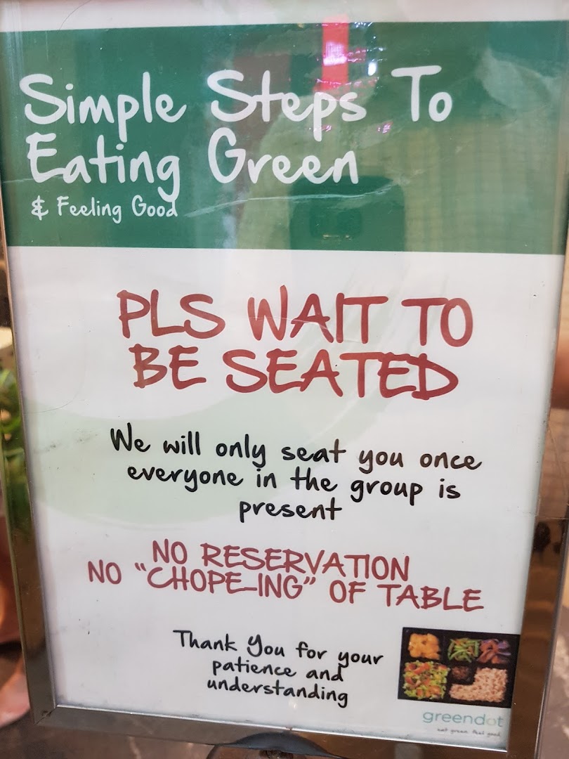 A sign at Greendot restaurant outlining seating policies and promoting healthy eating.