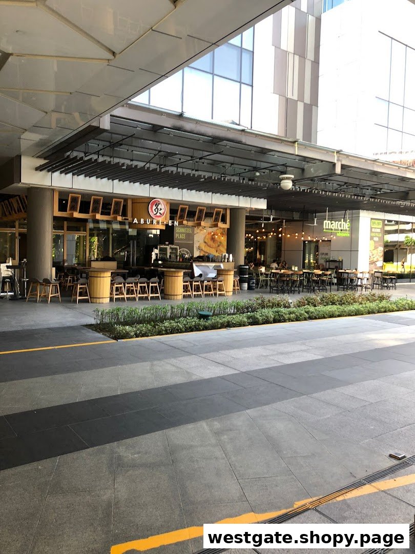 Outdoor dining area featuring multiple restaurant storefronts and seating under a modern building canopy.