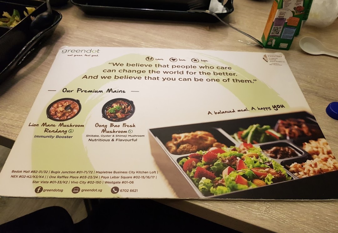 A Greendot placemat showcasing premium plant-based mains, a bento box, and the brand's philosophy.