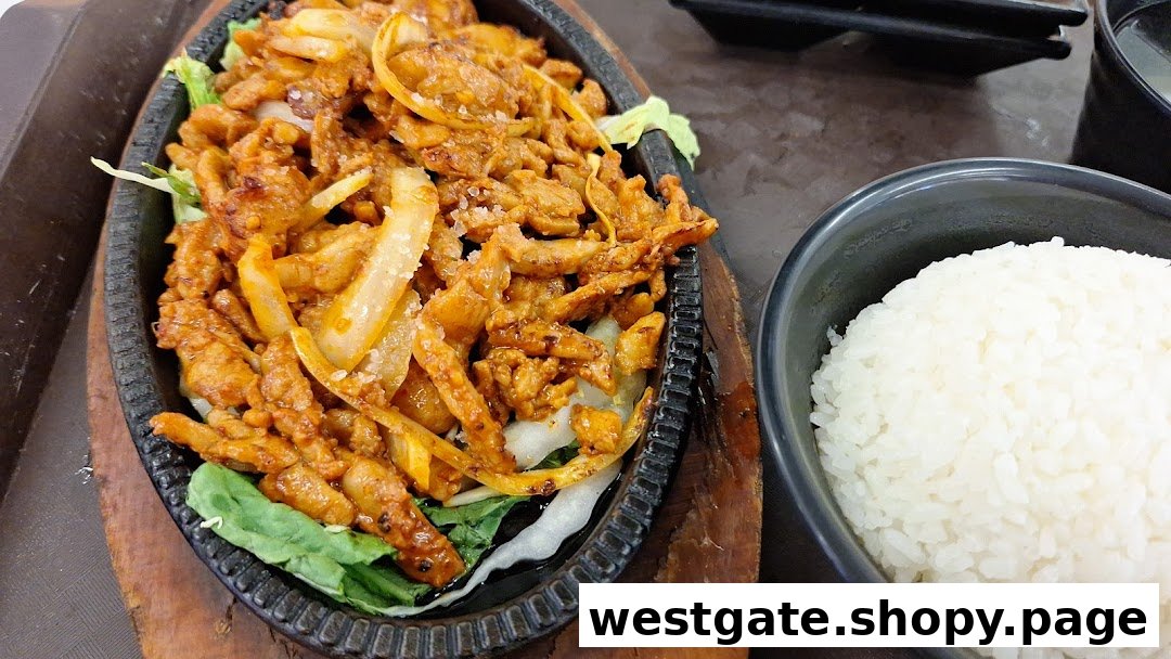 A sizzling plate of spicy Korean stir-fried meat with onions and lettuce, served with a bowl of white rice.