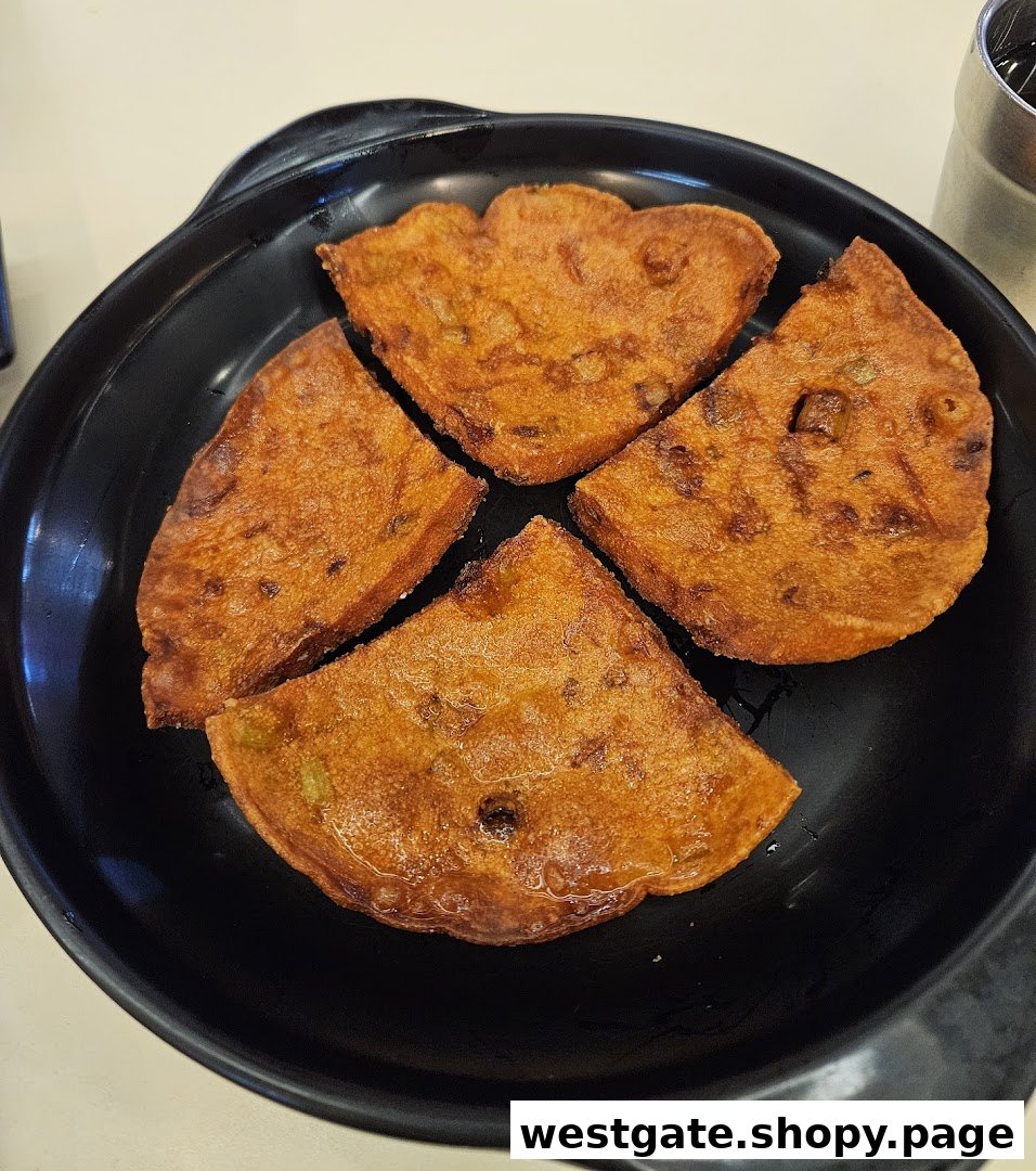 Four golden-brown fried pieces of food, possibly a type of fritter or pancake, served on a black plate.