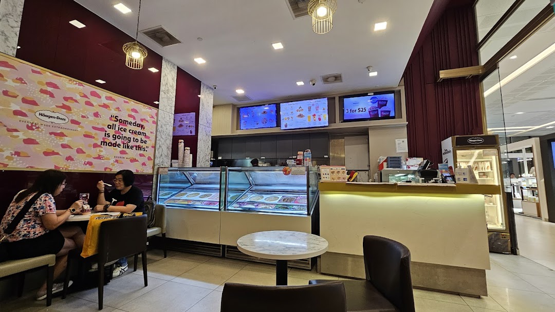 Interior view of a Häagen-Dazs ice cream shop with customers enjoying treats and display freezers.
